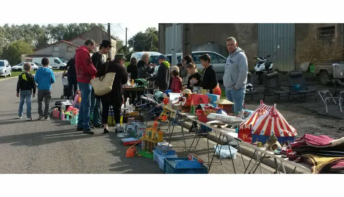 Stands de vide grenier installés sur une place avec des objets d'occasion posés sur des tables